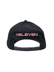 A back view of a black snapback baseball cap with hints of distressed texture and with embroidered pink 11.11 logo on a white backdrop. The cap also shows the adjustable snapback cap strap.