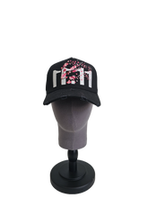 A front view of a black snapback baseball cap on a mannequin head with hints of distressed texture and with embroidered pink floral blossom patterns between the 11.11 logo on a white backdrop.