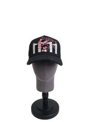 A front view of a black snapback baseball cap on a mannequin head with hints of distressed texture and with embroidered pink floral blossom patterns between the 11.11 logo on a white backdrop.
