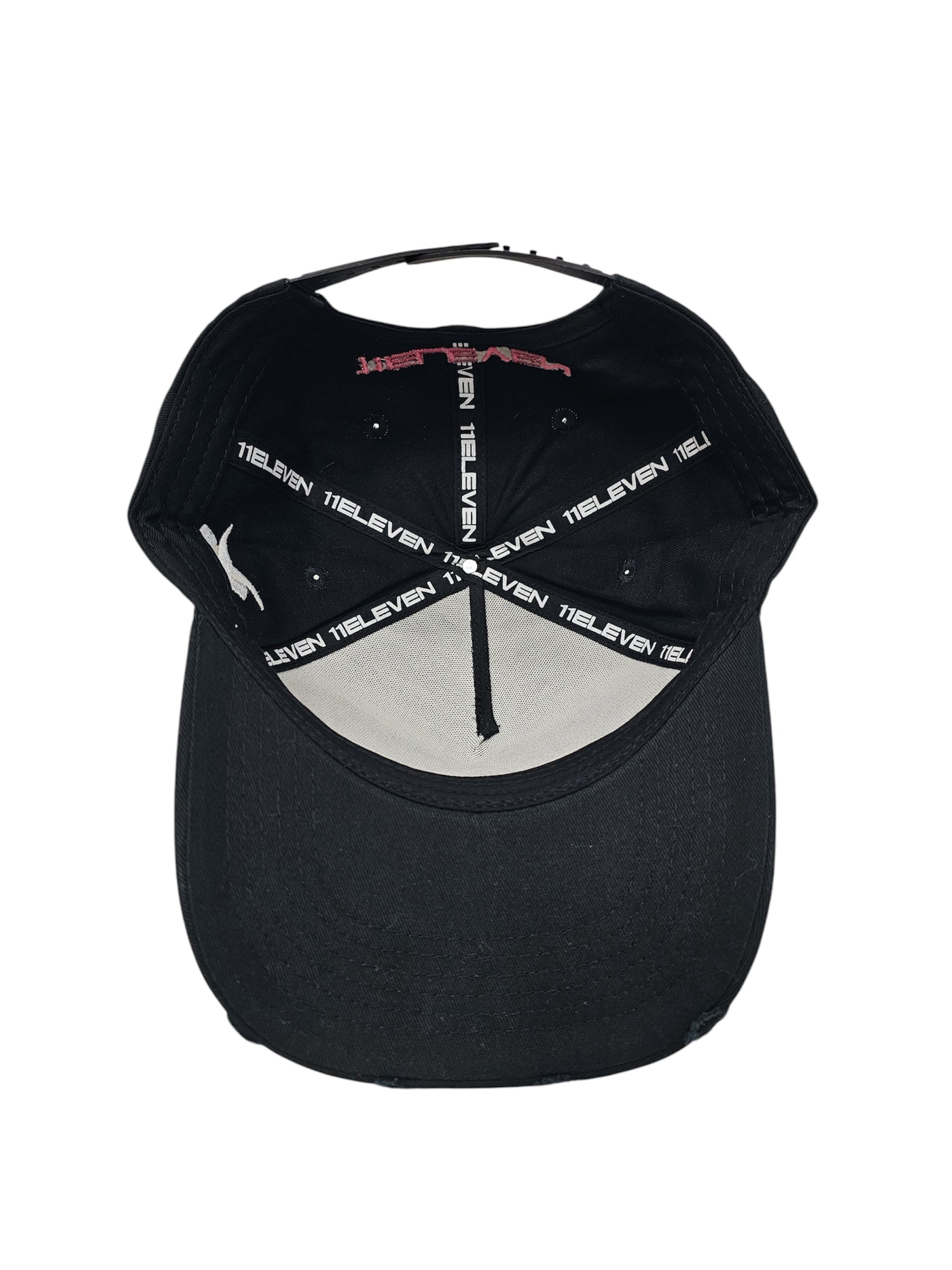 An angled view of a black snapback baseball cap with hints of distressed texture and with embroidered pink floral blossom patterns between the 11.11 logo on a white backdrop. The inside of the cap shows the 5 panel cap with seams printed with the "11ELEVEN" logo.