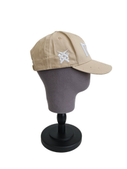 A left sided view of a beige snapback baseball cap on a mannequin head with an embroidered white 11.11 number logo, as well as a embroidered white 11ELEVEN symbol logo on the left side of the cap