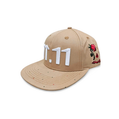 A right angled view of a beige snapback baseball cap with an embroidered white 11.11 number logo, also revealing The Broken Roses Illustration on the right side of the cap on a white backdrop.