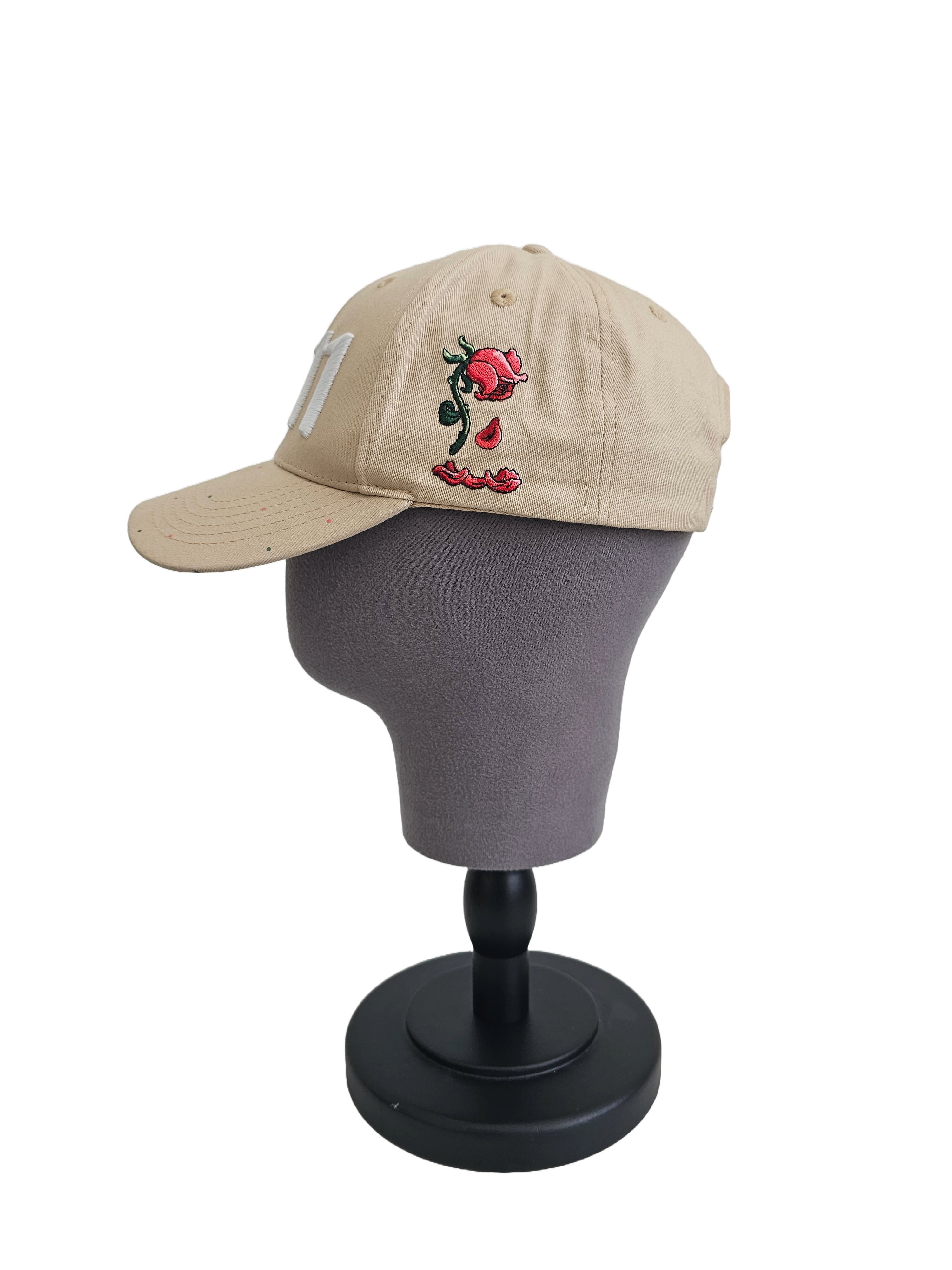 A right sided view of a beige snapback baseball cap on a mannequin head with an embroidered white 11.11 number logo, also revealing The Broken Roses Illustration on the right side of the cap