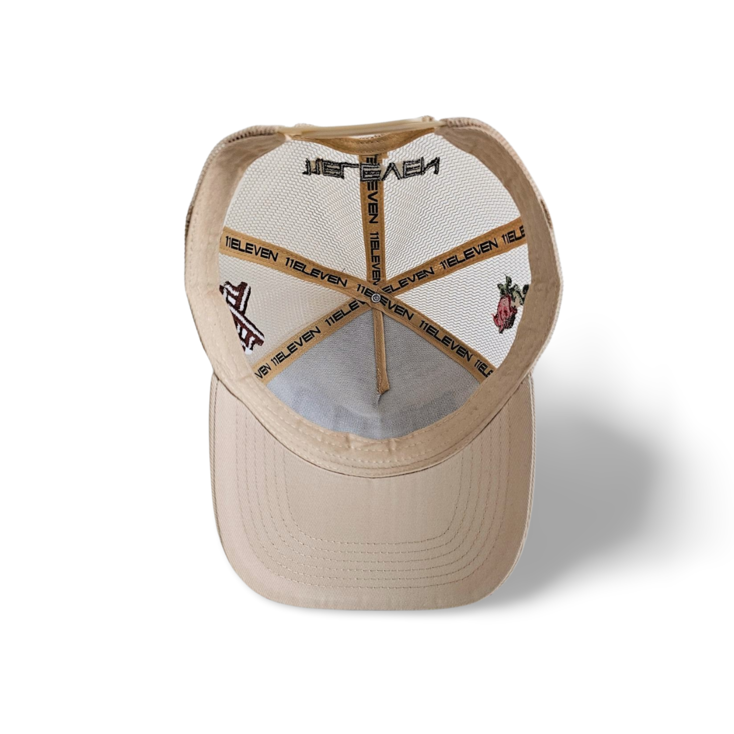 An inside view of a beige snapback trucker cap with an embroidered black 11.11 logo on a mesh trucker snapback cap with an adjustable cap strap on a white backdrop. The seams of the cap inside are lined with the 11ELEVEN logo.