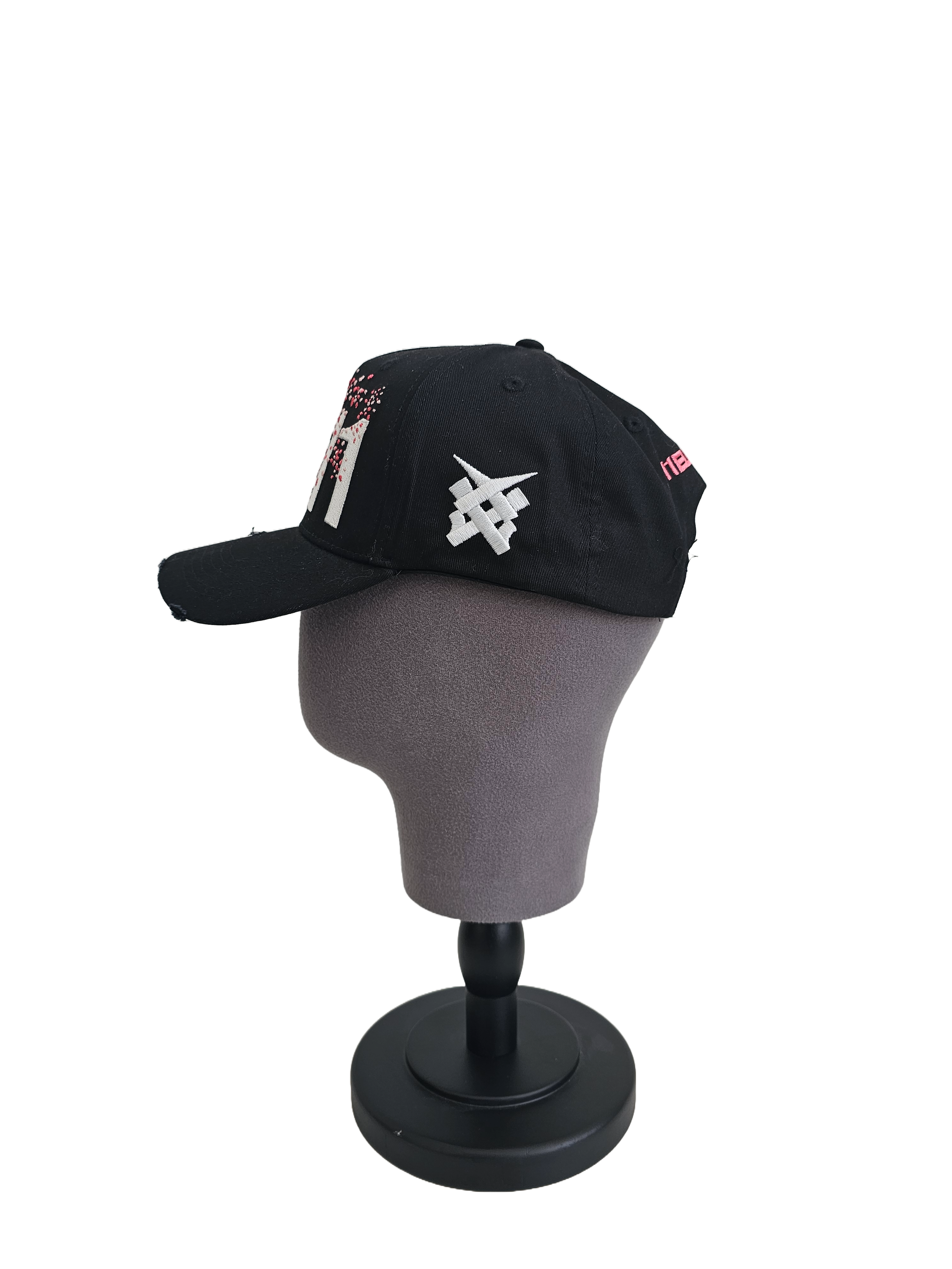 A right sided view of a black snapback baseball cap on a mannequin head with hints of distressed texture and with embroidered pink floral blossom patterns between the 11.11 logo on a white backdrop. The right side of the cap has a white embroided 11.11 symbol logo on it