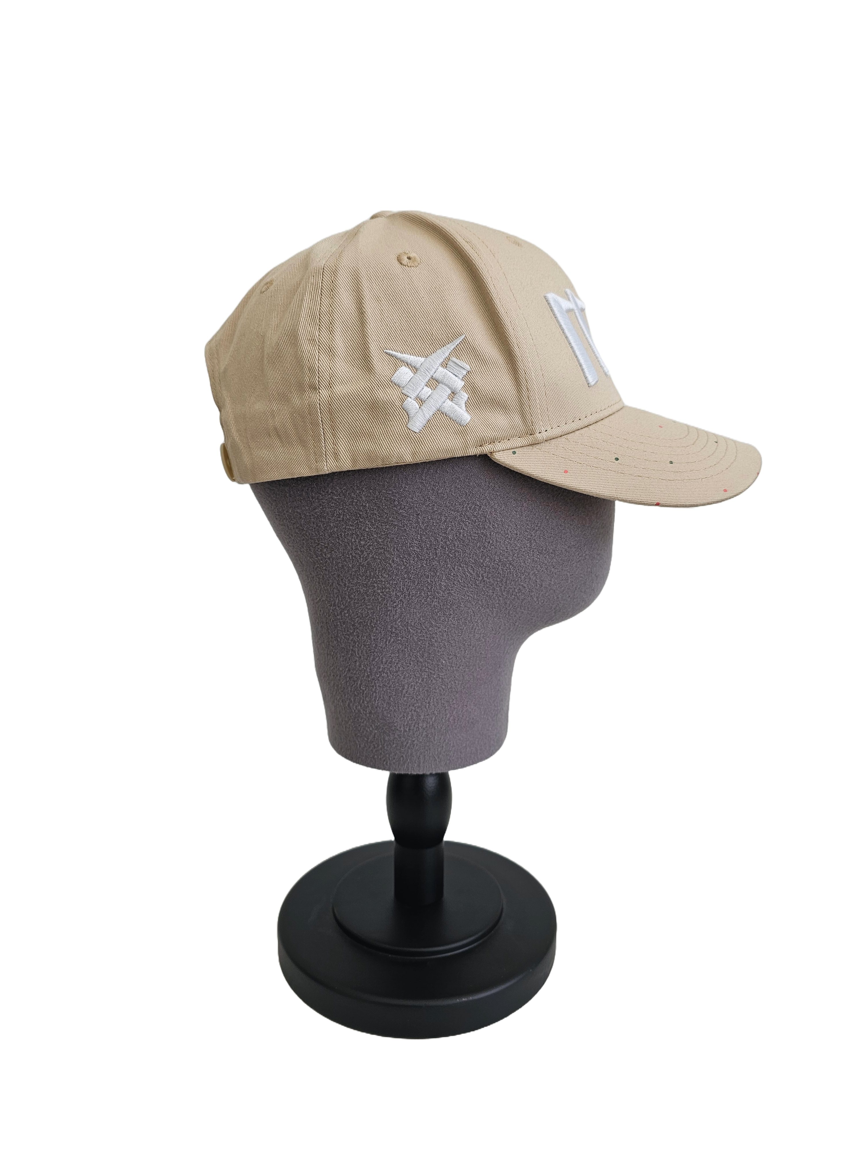 A left sided view of a beige snapback baseball cap on a mannequin head with an embroidered white 11.11 number logo, as well as a embroidered white 11ELEVEN symbol logo on the left side of the cap